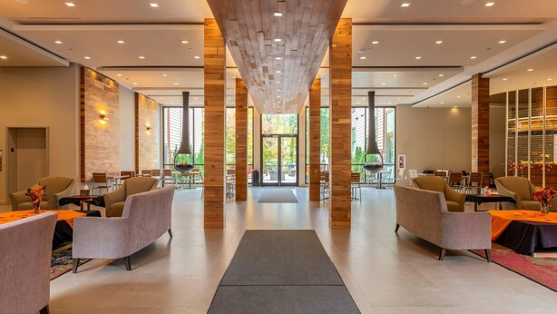 A spacious lobby with modern furniture, a central walkway, and large windows.