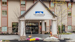 A hotel with a prominent entrance, large windows, and a landscaped front yard with rocks and flowers.