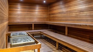 A sauna with wooden walls and benches, equipped with metal grates for water drainage.