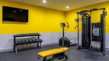 A gym with a bench, dumbbells, and a squat rack.