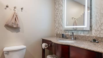 A bathroom with a toilet, sink, mirror, towel rack, and a hanging bag labeled 'HAIRDRYER'.