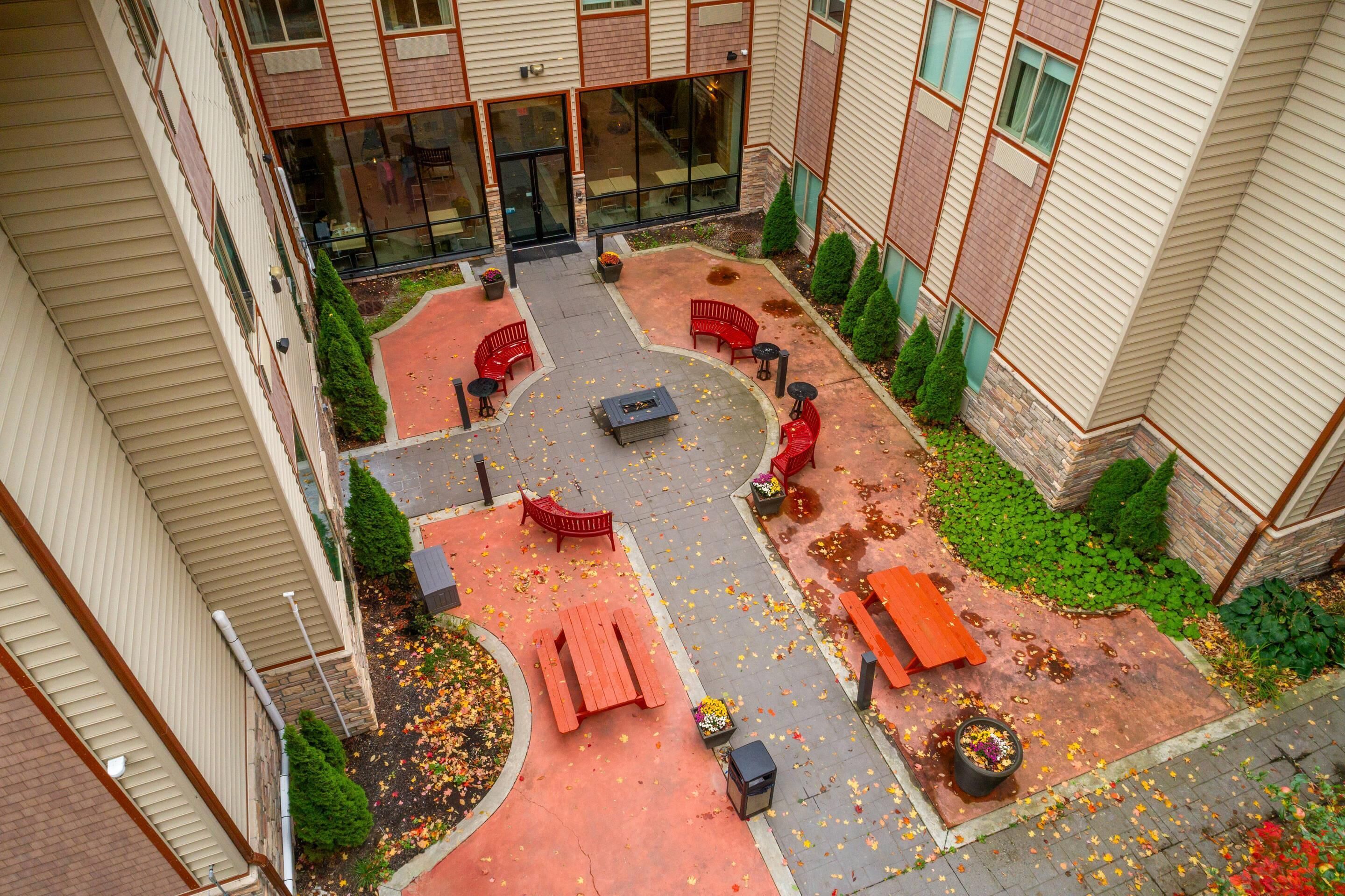 Vue aérienne d’une cour avec des espaces de détente en plein air, un foyer et des plantes en pot.