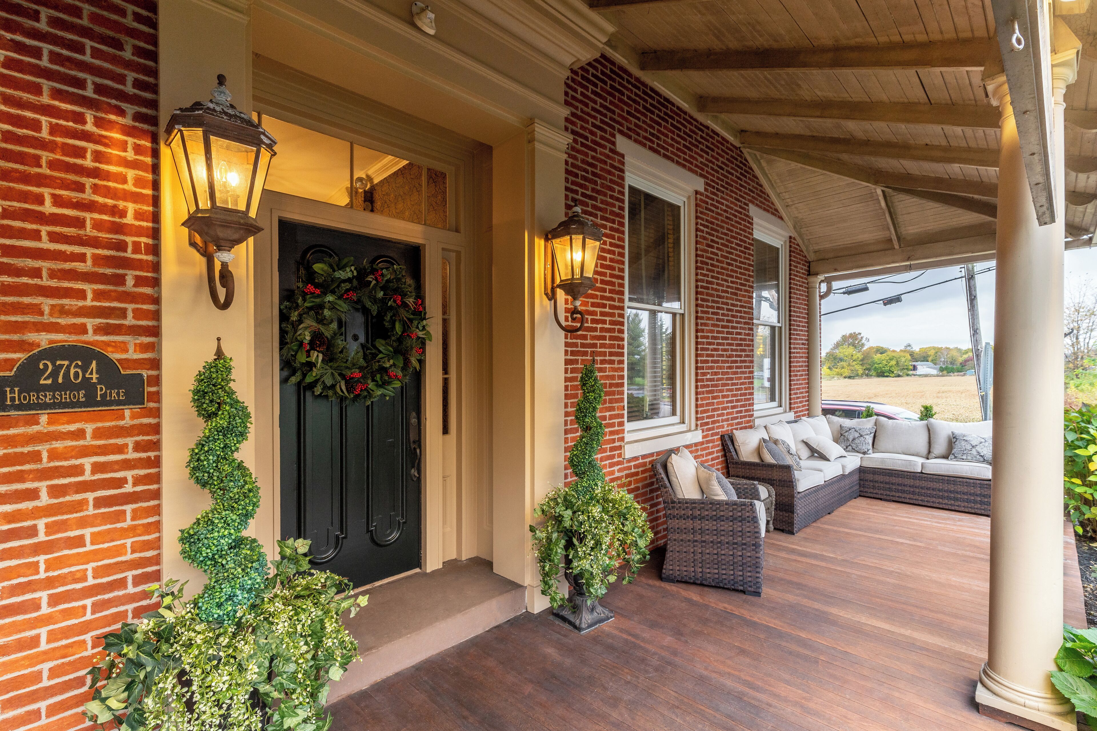 A brick house with a porch, a black door, and a sign reading "2764 Horseshoe Pike".