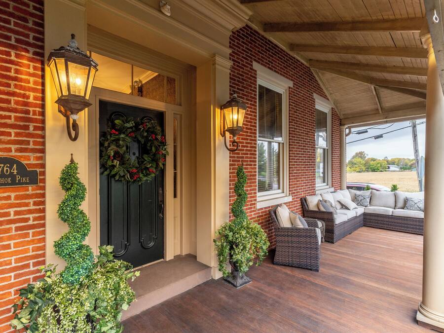 A brick house with a porch, a black door, and a sign reading "2764 Horseshoe Pike".