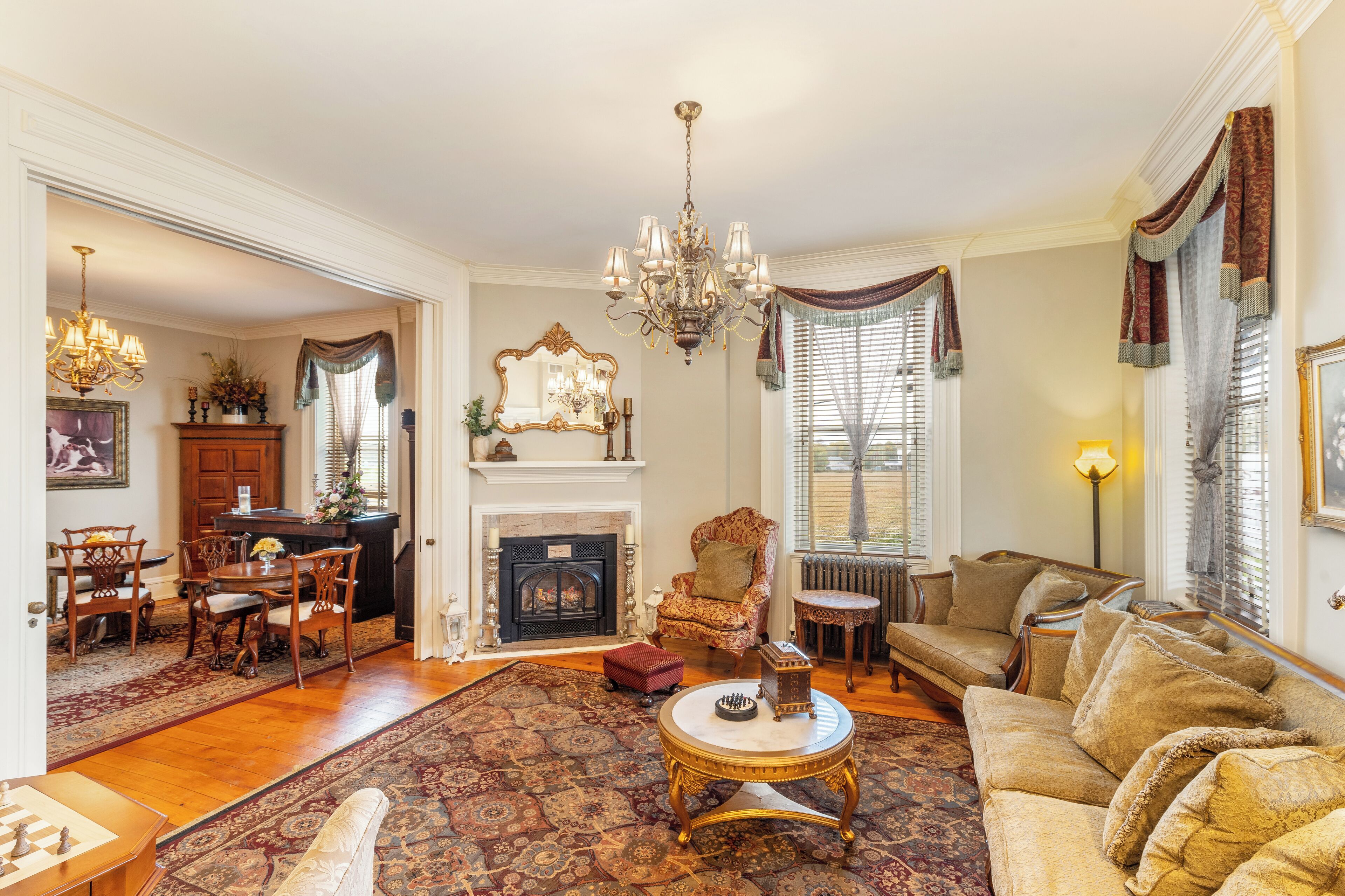 A spacious living room with a fireplace, a chandelier, and a large rug.