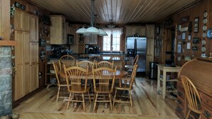 A wooden cabin-style kitchen with a central island, wooden chairs, a refrigerator, and a dining table. - Innisfaire (Traverse City)