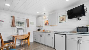 Una cocina moderna con muebles blancos, un microondas integrado y un televisor de pantalla plana grande.