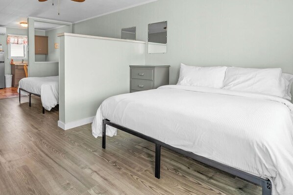 A bedroom with a large bed, a dresser, and a mirror. - Echo Motel & Oceanfront Properties (Old Orchard Beach)