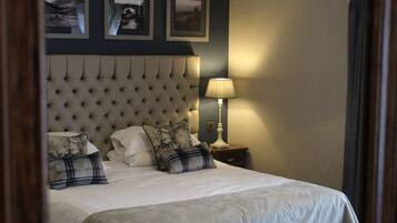 A neatly made bed with a tufted headboard, a bedside lamp, and three framed pictures on the wall.