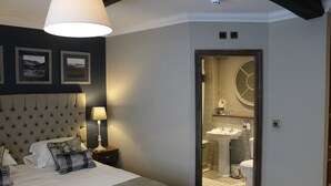 A bedroom with a tufted headboard, a bed with white linens, and a bedside table with a lamp.