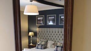A bedroom with a large bed, a bedside table with a lamp, and a mirror reflecting the room. - Red Dragon Inn (Carnforth)