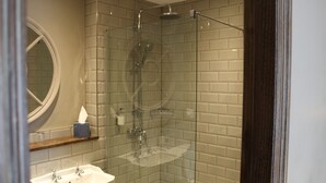 A bathroom with a glass-enclosed shower, a sink, and a mirror. - Red Dragon Inn (Carnforth)