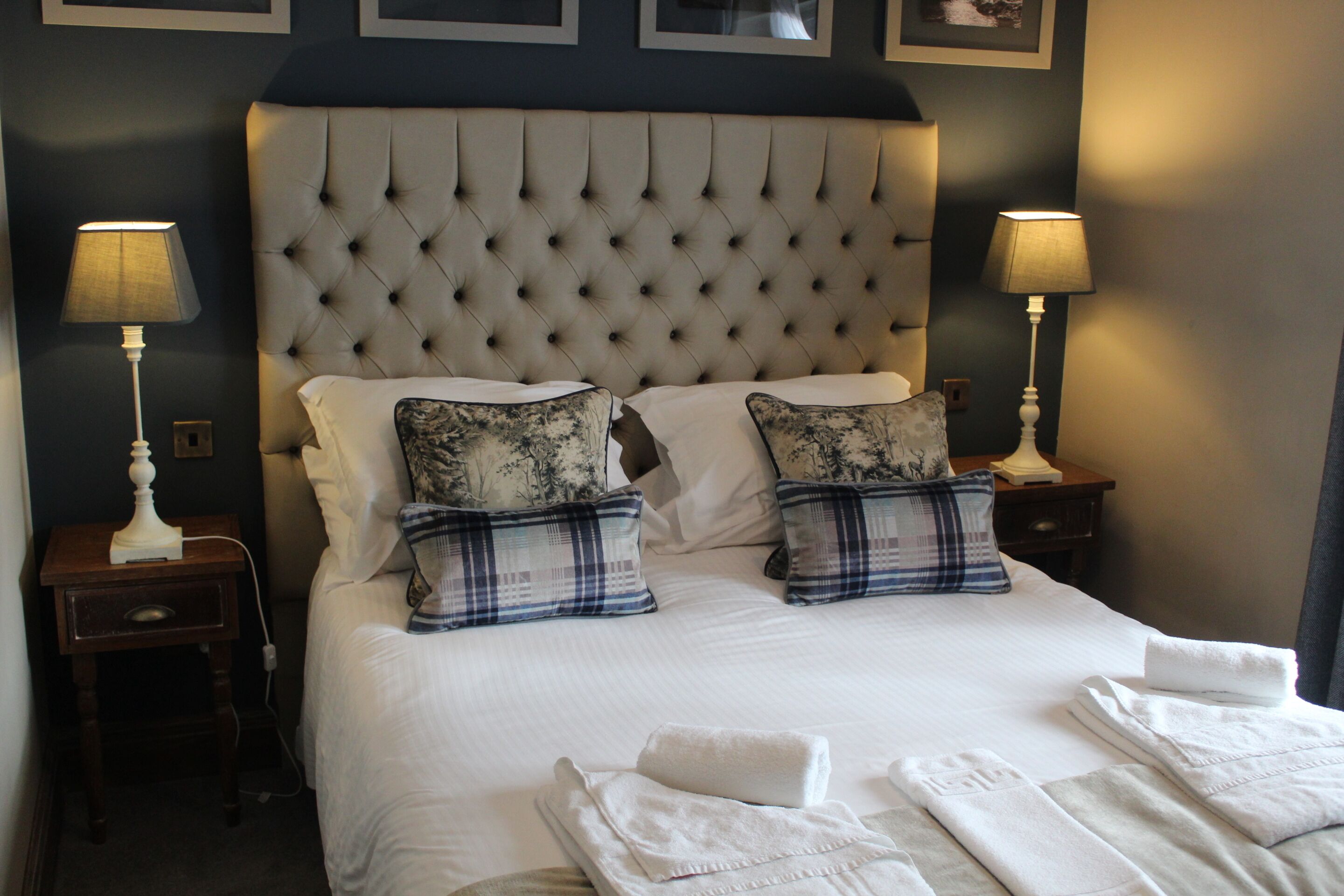 A neatly made bed with two pillows, a headboard, and two bedside lamps.