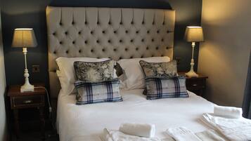 A neatly made bed with two pillows, a headboard, and two bedside lamps.
