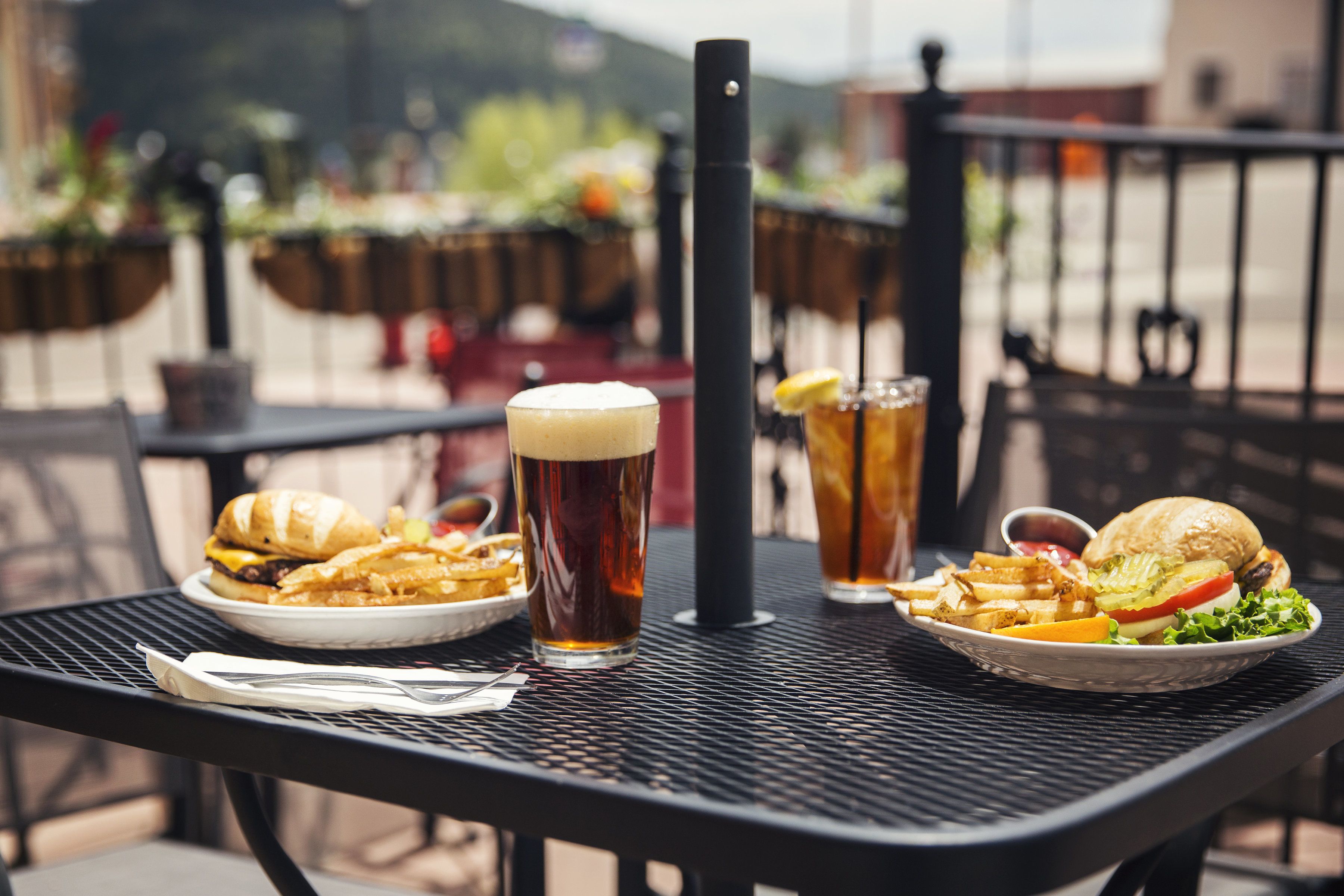 A table with food and drinks, including burgers, fries, and beer glasses.