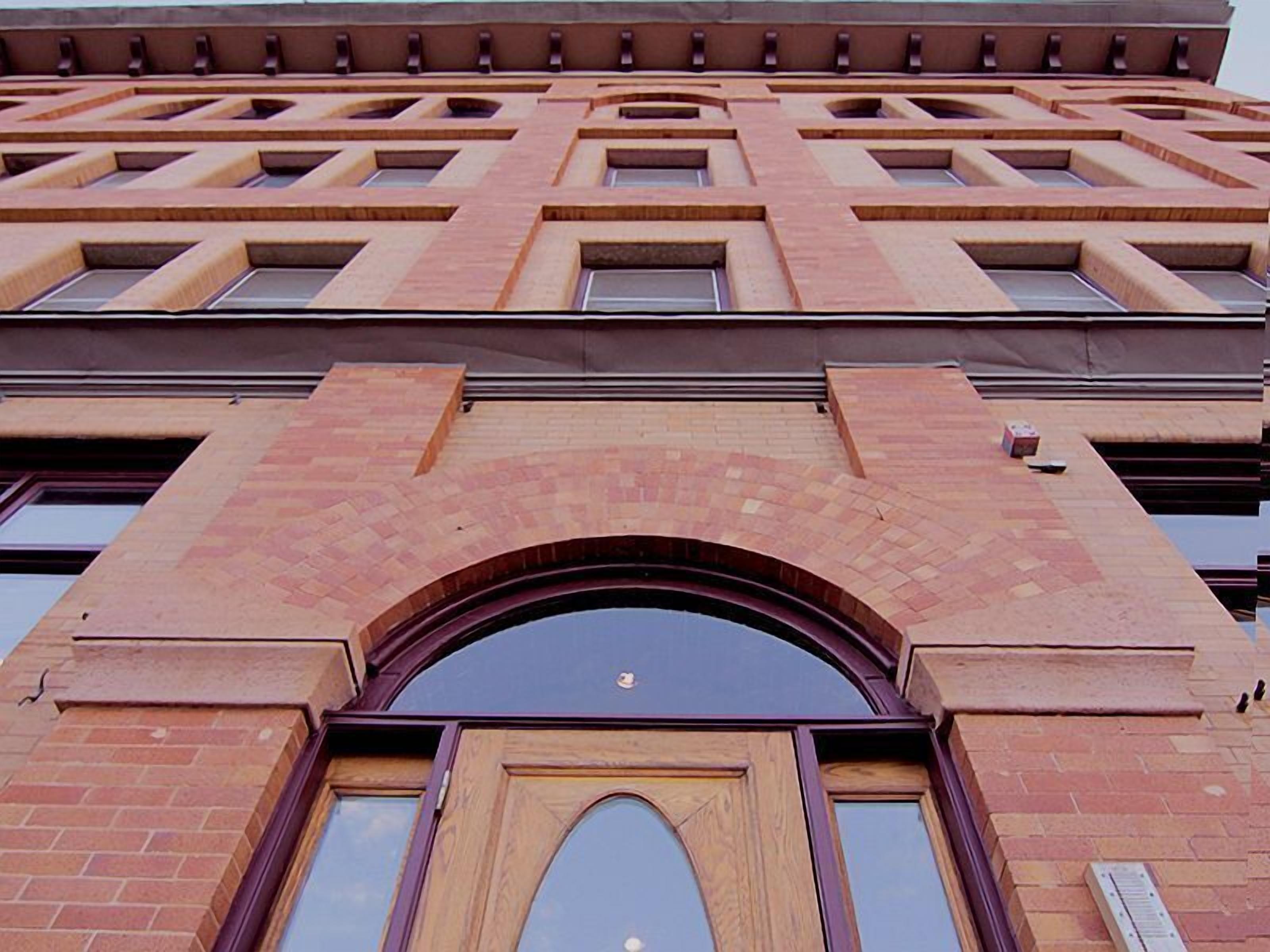 Un edificio de varios pisos con una entrada arqueada destacada y una serie de ventanas rectangulares.