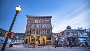 A multi-story brick building with large windows and a prominent entrance. - Victor Hotel (Victor)