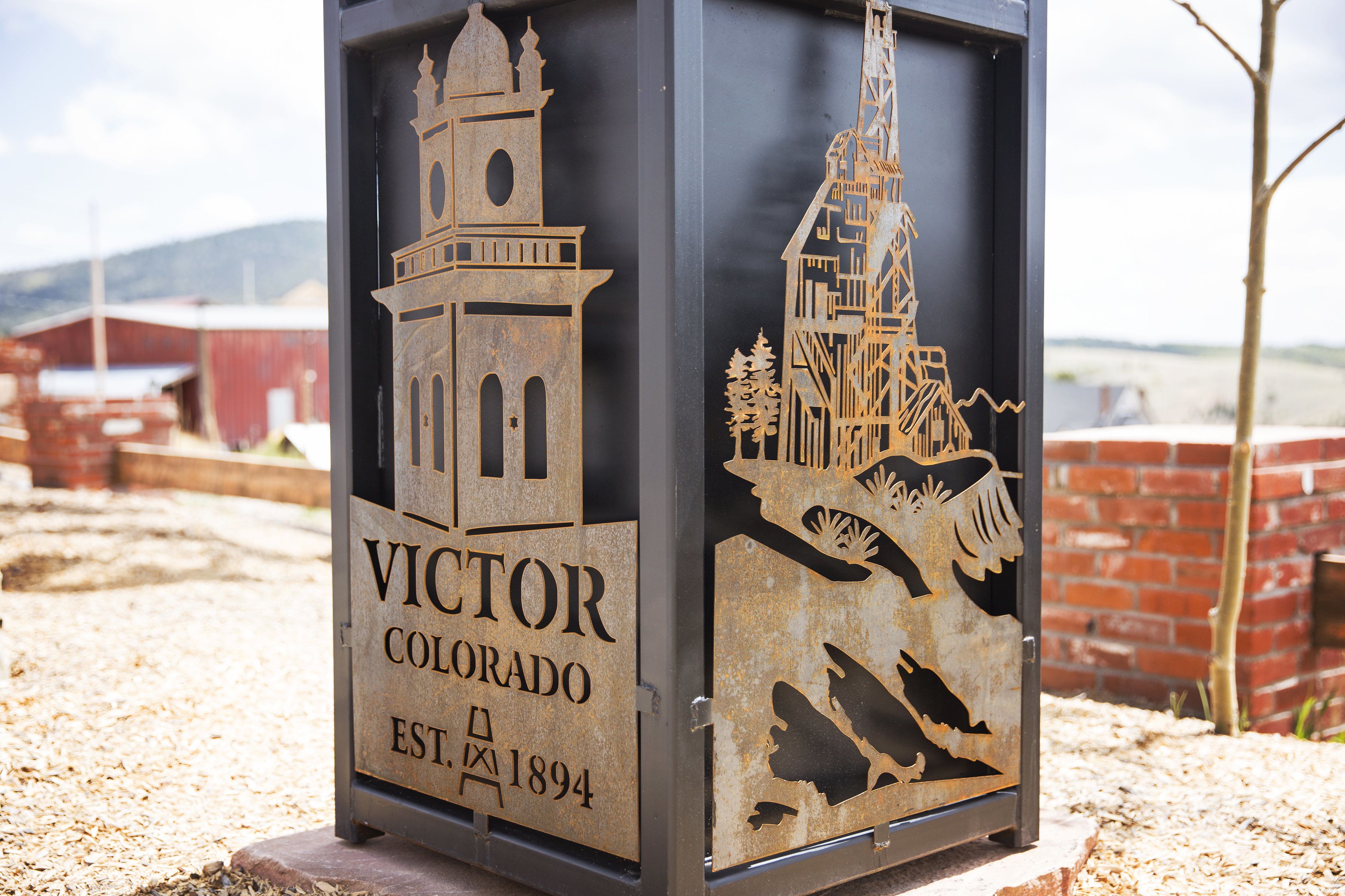 Een metalen bord met de tekst 'VICTOR COLORADO EST. 1894' en twee architecturale silhouetten.