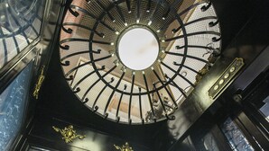 A circular skylight with a grid pattern and ornate metalwork. - Victor Hotel (Victor)