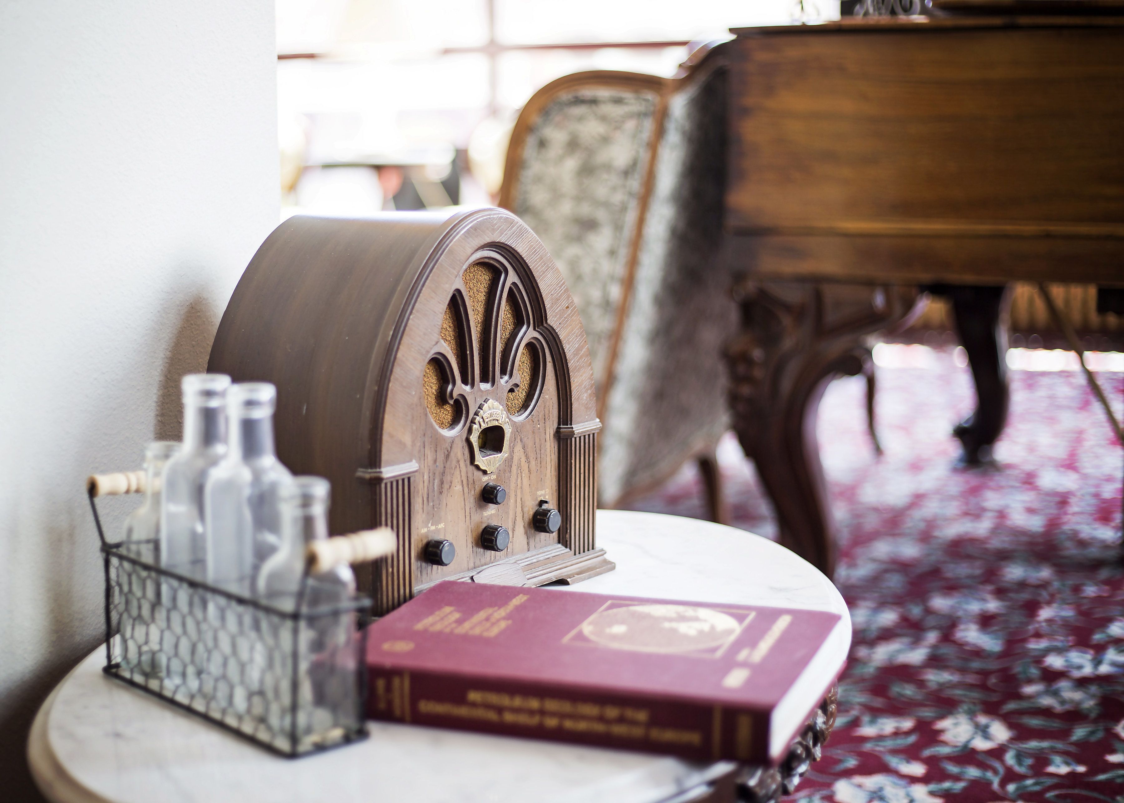 A vintage radio on a table with a book and a glass container.
