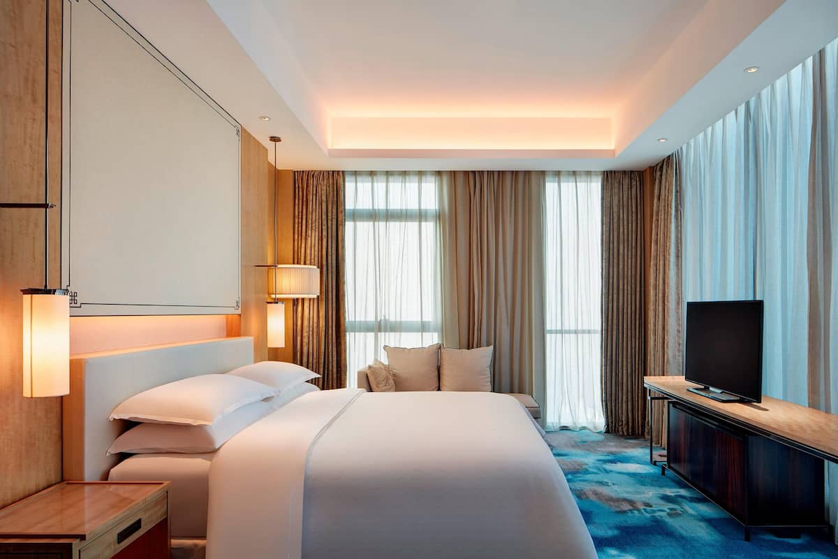 Ein modernes Hotelzimmer mit einem großen Bett, einem Fernseher und einem Schreibtisch.