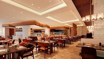 A spacious restaurant with multiple dining areas, a bar, and a kitchen visible in the background.