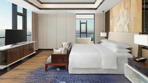 Habitación de hotel moderna con una cama grande, televisor, escritorio y vistas a la ciudad.