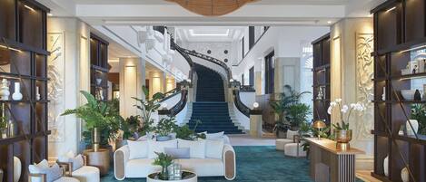 A spacious lobby with a central staircase, modern furniture, and decorative plants.