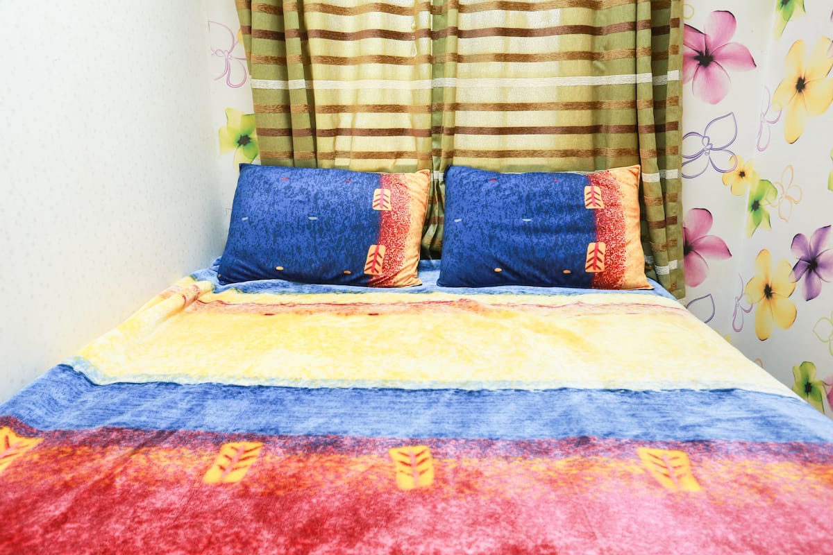 A bed with a colorful bedspread and striped curtains.