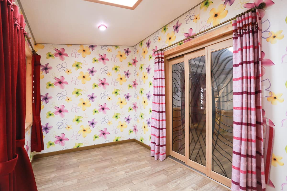 A room with floral wallpaper, a sliding glass door, and a wooden floor.