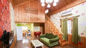 Ein Holzinterieur mit einem grünen Sofa, einem weißen Couchtisch, einer Treppe und einer Küchenzeile.