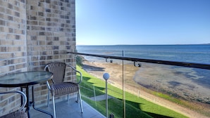 Ein Balkon mit Blick auf den Strand, ein Tisch und zwei Stühle.