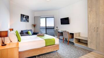 A modern hotel room with a bed, desk, and TV.