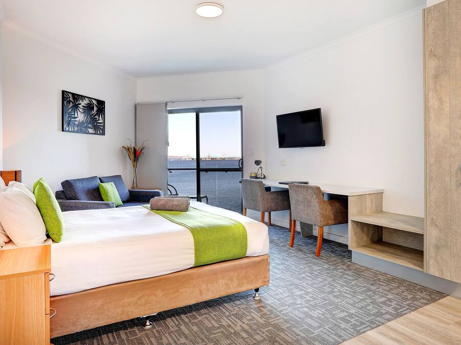 A modern hotel room with a bed, desk, and TV.