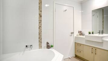 A modern bathroom with a freestanding bathtub, a vanity with a mirror, and a door leading to another room.