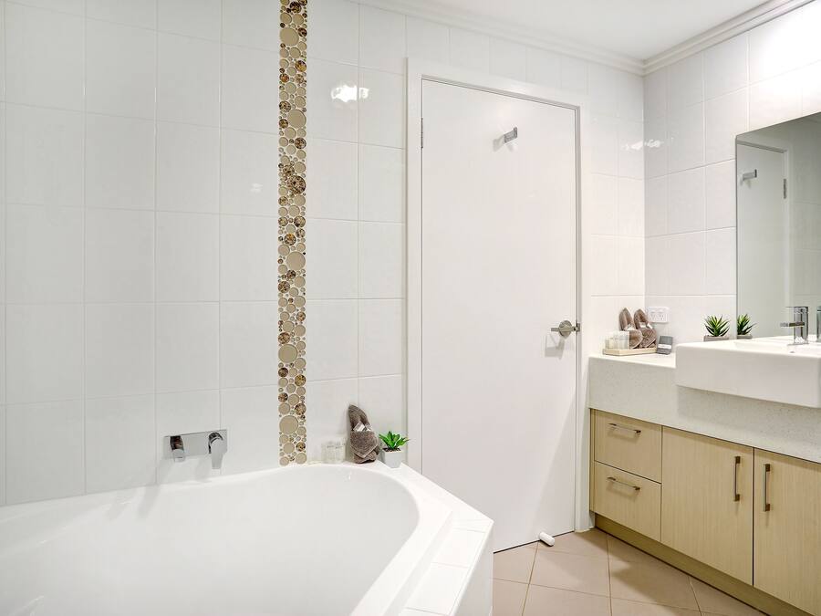 A modern bathroom with a freestanding bathtub, a vanity with a mirror, and a door leading to another room.