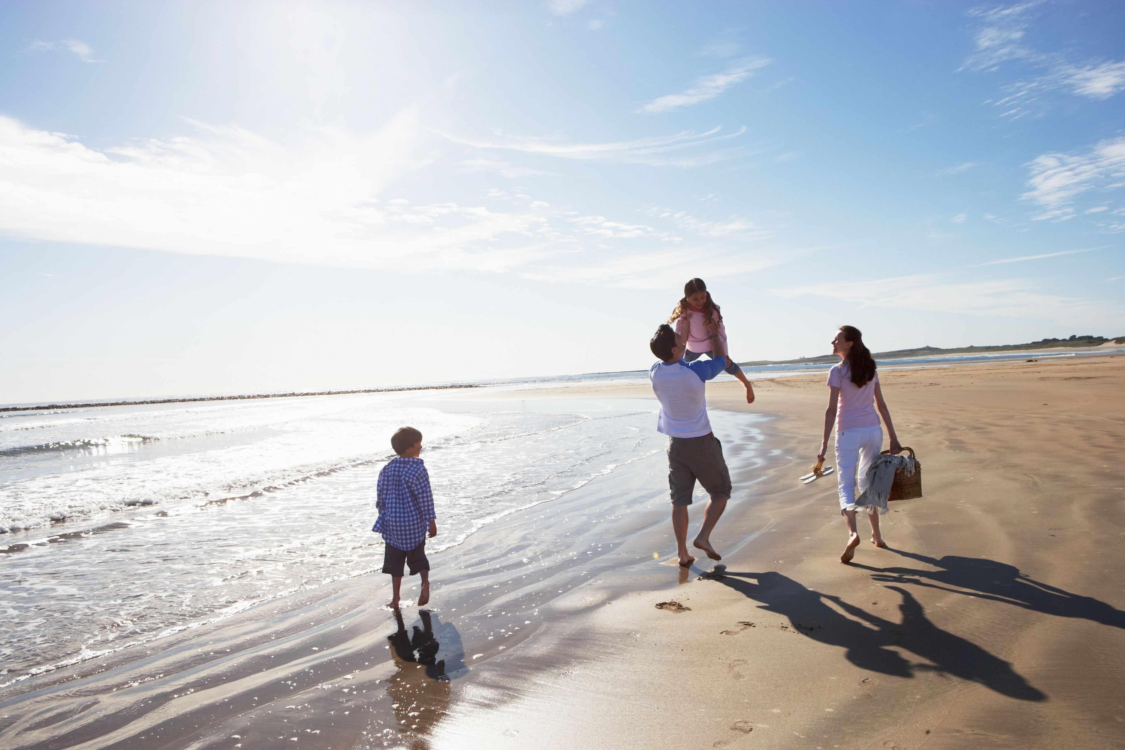 A family walking on a sandy beach with a clear sky.