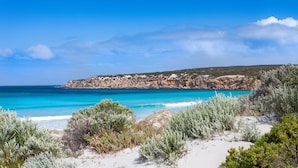 Eine Küstenlandschaft mit freiem Blick auf das Meer, einem Sandstrand und Felsen.