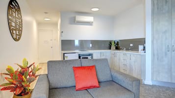 En moderne stue med en grå sofa, en rød pude og et dekorativt vægkunstværk.