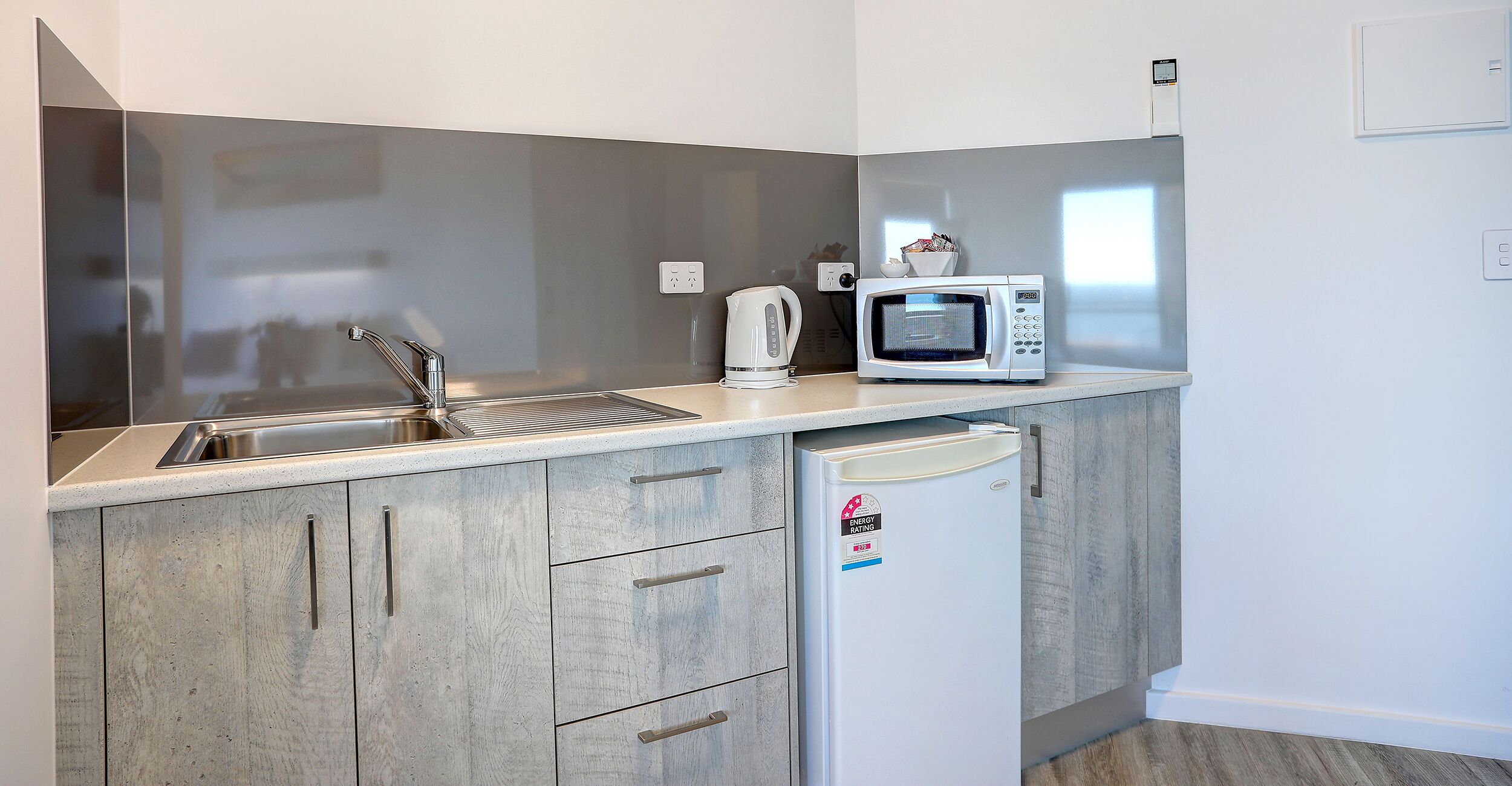 A compact kitchen with a sink, microwave, and a small refrigerator.