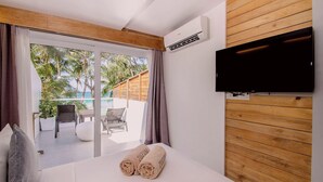 A hotel room with a bed, a TV mounted on the wall, and a view of a balcony with outdoor furniture. - Zuzuni Boutique Hotel (Boracay Island)