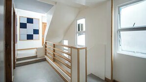A narrow hallway with a wooden railing, a small window, and a door with a checkered pattern. - Zuzuni Boutique Hotel (Boracay Island)