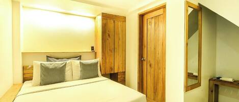A bedroom with a bed, wooden wardrobe, and a mirror.