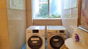 Zona de bugaderia amb dues rentadores i una ampolla de detergent sobre una taula.