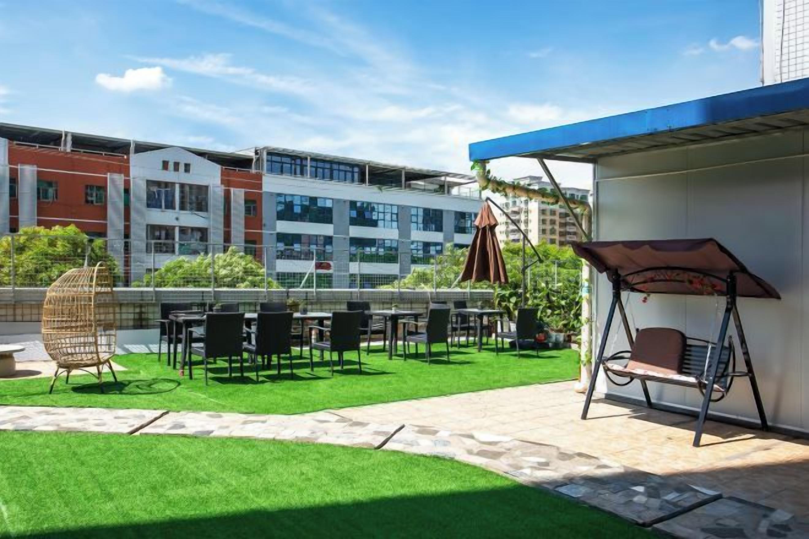 An outdoor patio with artificial grass, seating, and a swing chair.