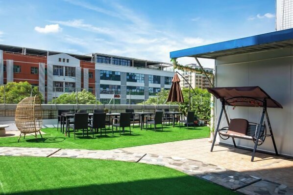 An outdoor patio with artificial grass, seating, and a swing chair.