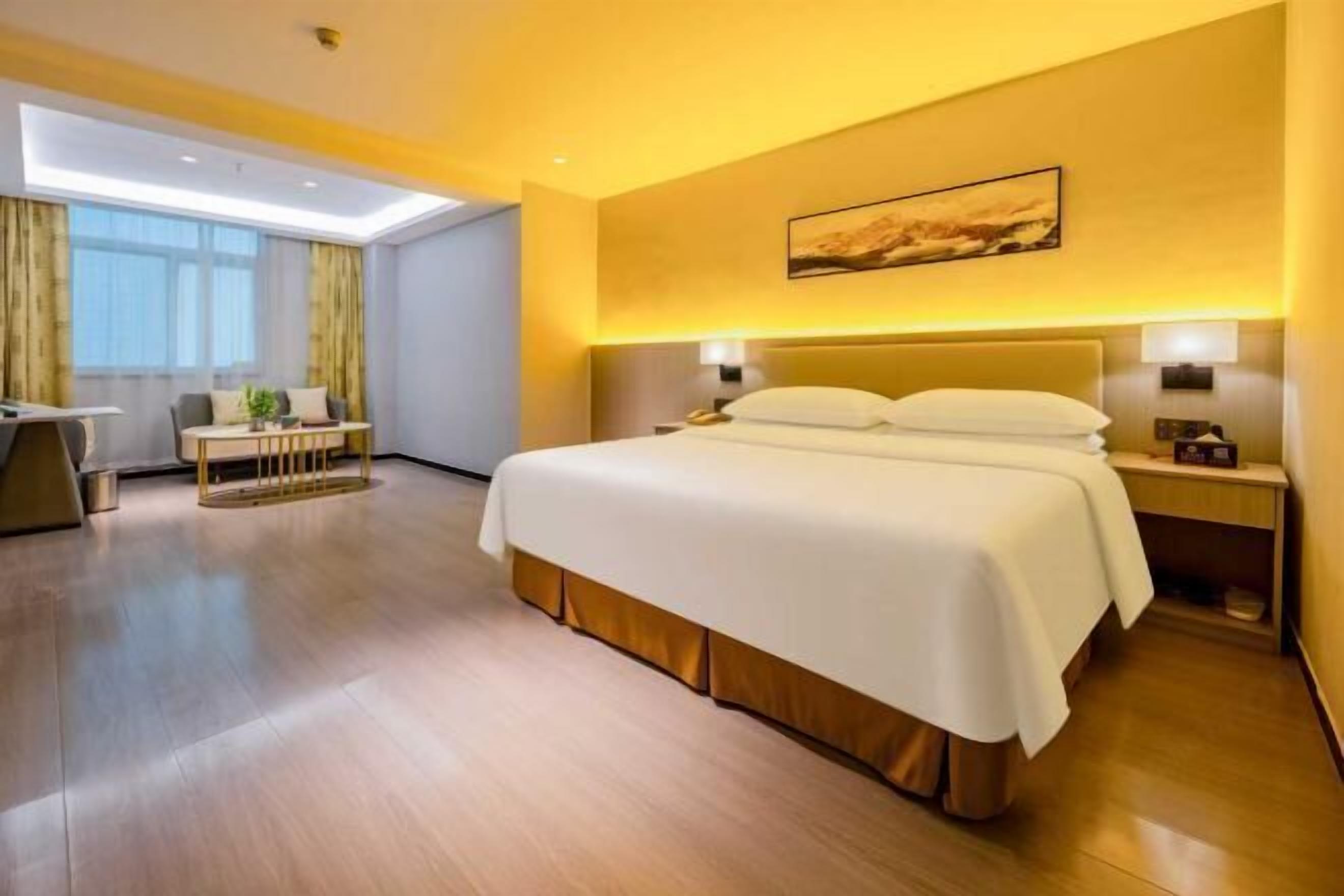 A hotel room with a large bed, bedside tables, a desk, and a chair.