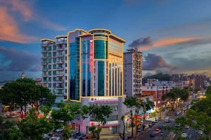 A multi-story hotel with a modern design, featuring a prominent vertical sign and a well-lit facade.