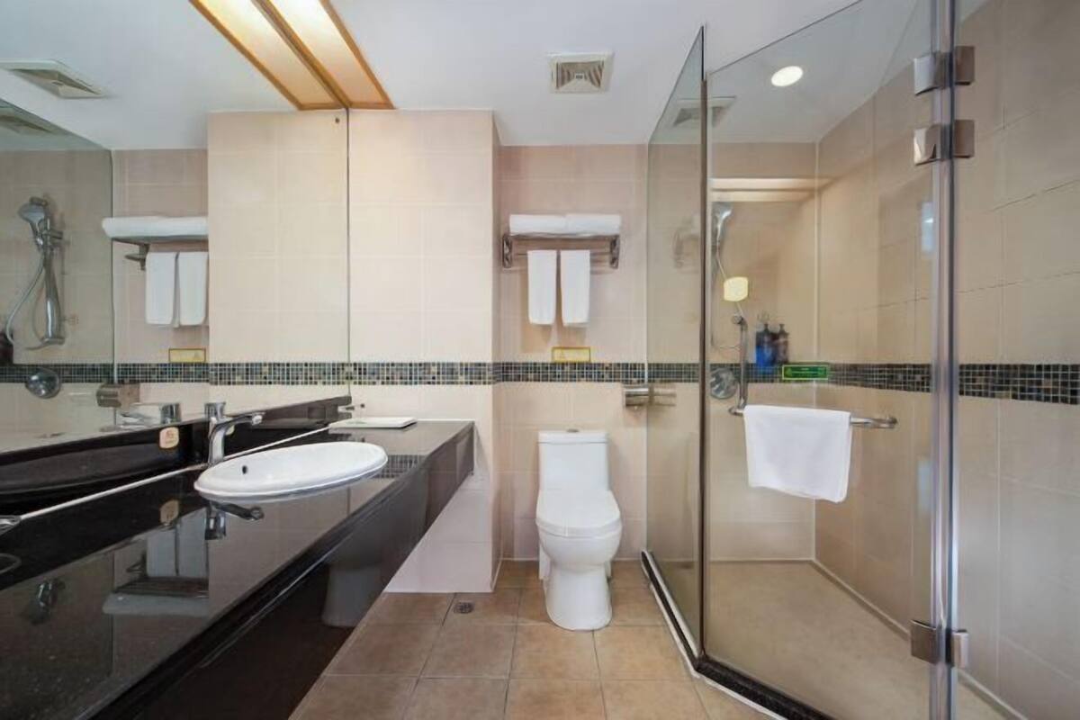 A modern bathroom with a glass-enclosed shower, a white toilet, and a black vanity with a sink.
