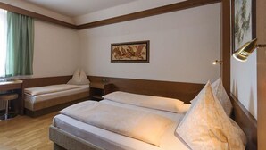 A hotel room with a double bed, a desk, a chair, and a painting on the wall. - Tautermann Garni (Innsbruck)
